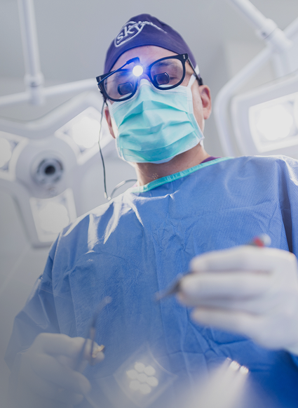 Surgeon wearing gloves and surgical mask in operation.