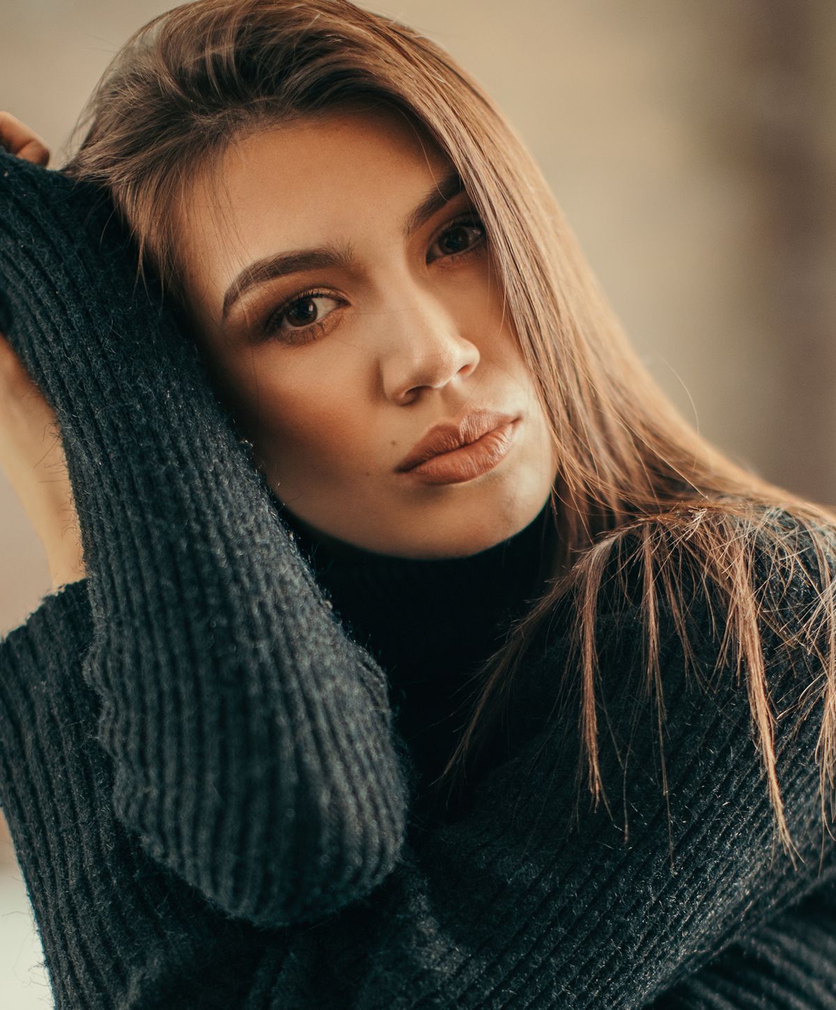Woman in cozy black sweater looking thoughtfully.