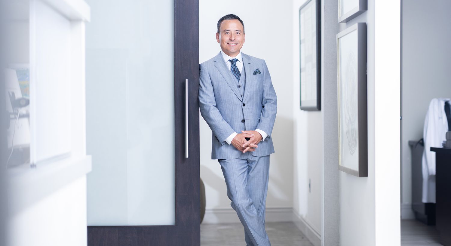 Man in gray suit standing by open door.