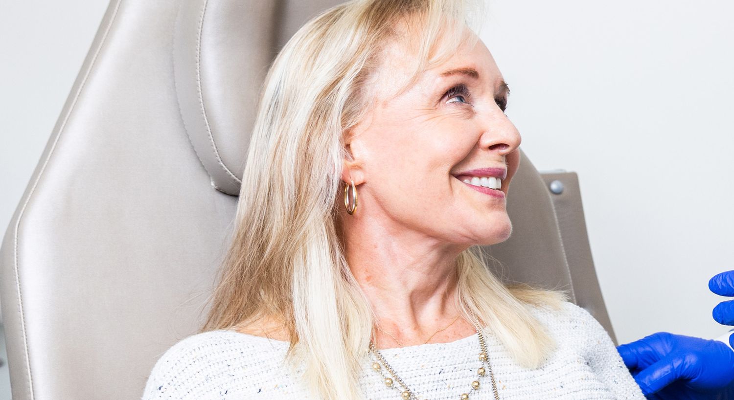 Woman smiling during a cosmetic treatment session.